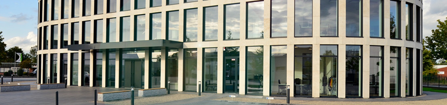 Modernes Bürogebäude mit bodentiefen Fenstern und heller Natursteinfassade